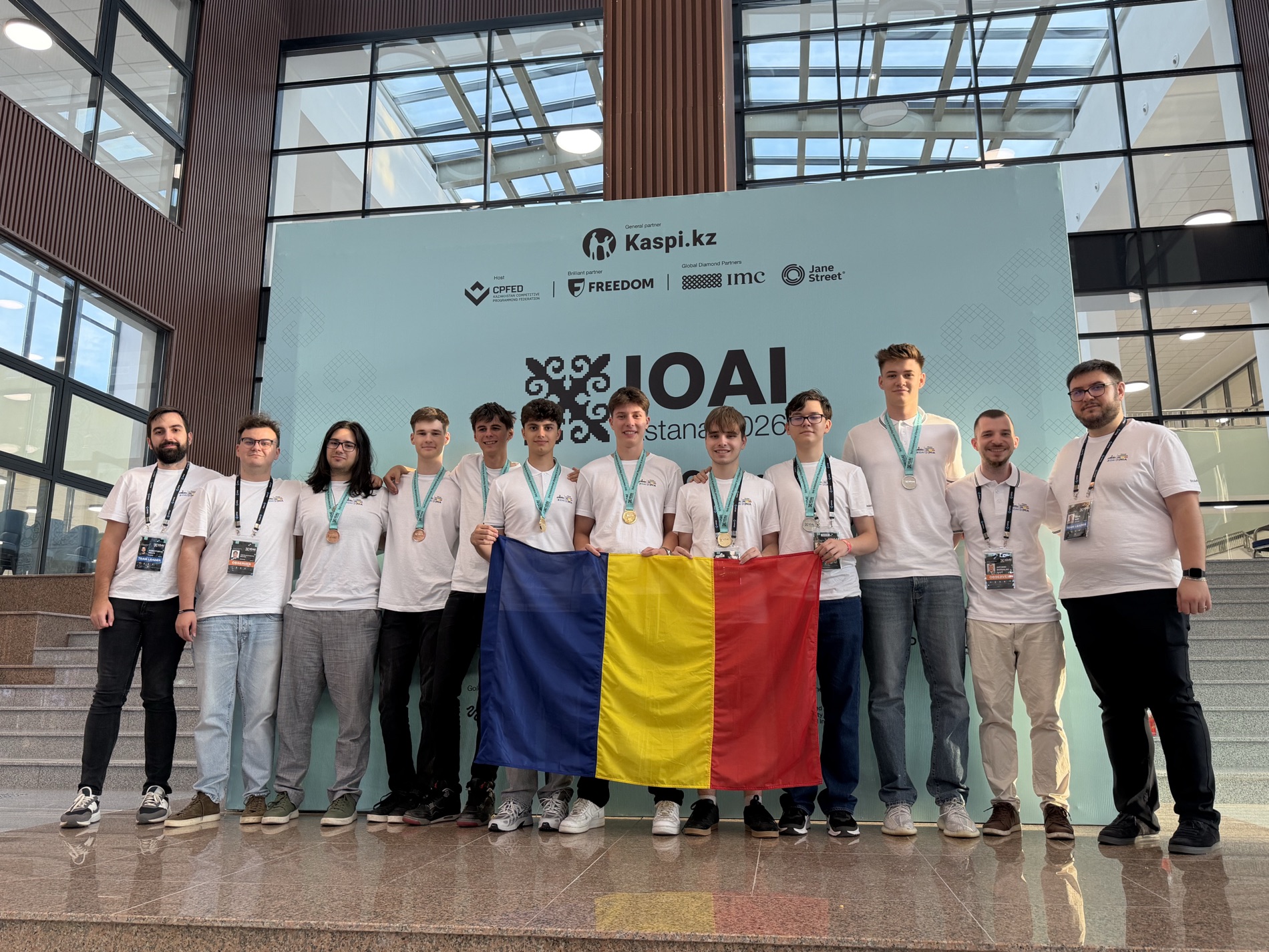Team Romania at IOAI Astana 2026, holding the Romanian flag, wearing medals